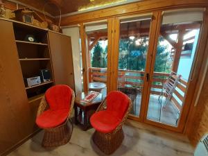 维索科Obiteljski Apartman Borovi的一间设有红色椅子、桌子和窗户的房间