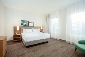圣贝纳迪诺Staybridge Suites - San Bernardino - Loma Linda的卧室配有床、椅子和窗户。