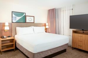圣贝纳迪诺Staybridge Suites - San Bernardino - Loma Linda的配有一张床和一台平面电视的酒店客房