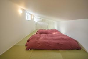 屋久岛KeiU-Yakushima Luxury Guest House的卧室配有红色的被子,位于地板上
