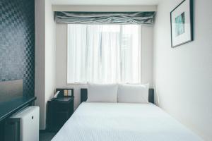 名古屋汉密尔顿酒店 布莱克的一间卧室配有一张带白色床单的床和一扇窗户。