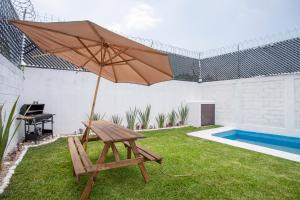 库奥特拉莫雷洛斯Casa con alberca privada y jardin的游泳池旁带遮阳伞的野餐桌