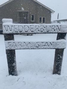 WedderburnWedderburn Farm Stay的房子前面的雪覆盖的长凳
