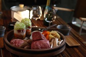 山中湖村THE DAY POST GENERAL GLAMPING VILLAGE Yamanakako的桌上放着一碗肉和蔬菜,放着酒杯