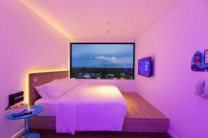 Vị ThanhSOJO Hotel Hau Giang的粉红色的卧室设有床和大窗户
