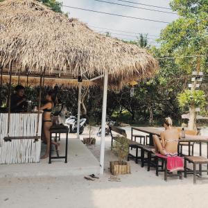 阁帕延岛Tropical Hostel的一群人坐在稻草伞下的长椅上