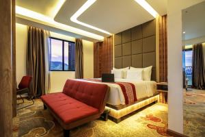 TakengonParkside Gayo Petro Hotel Takengon的酒店客房,配有一张床和一张红色的沙发