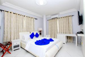 科托努Hotel Galilée的白色卧室配有一张带蓝色枕头的大床