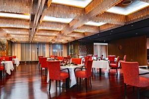 迪拜The Canvas Dubai - MGallery Hotel Collection的用餐室配有桌子和红色椅子