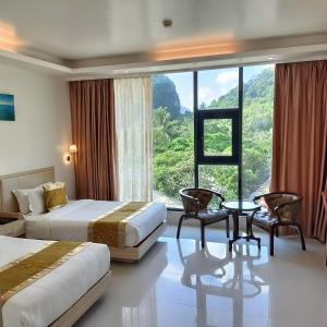 爱妮岛One El Nido Suite的酒店客房设有两张床和大窗户。