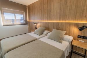 Santa Marta基卡酒店的配有木墙和窗户的客房内的两张床