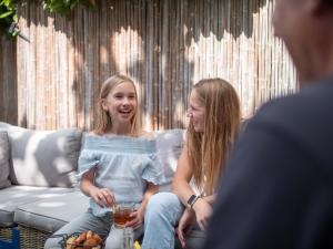 瓦赫宁根TopParken – Recreatiepark de Wielerbaan的坐在沙发上跟男人说话的年轻女孩