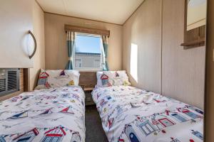 克利索普斯Waterside, Thorpe Park Cleethorpes Static Caravan的一间卧室设有两张床和窗户。