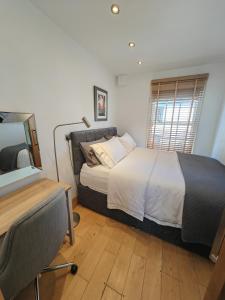 剑桥Cambridge city centre immaculate 2 bed apartment的一间卧室配有一张床、一张书桌和一个窗户。