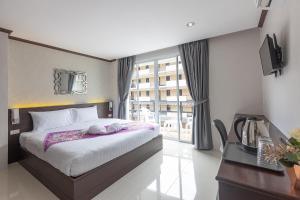 芭东海滩The Chic Patong的一间卧室配有一张床、一张书桌和一个窗户。