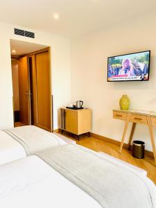 查韦斯Castelo Hotel的一间卧室设有两张床,墙上配有电视。