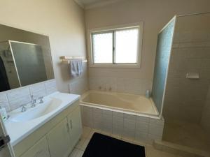 南黑德兰Four bedroom House on Masters South Hedland的带浴缸、水槽和淋浴的浴室