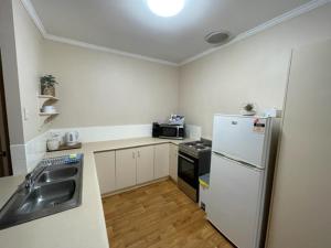 南黑德兰Four bedroom House on Masters South Hedland的白色的厨房配有水槽和冰箱