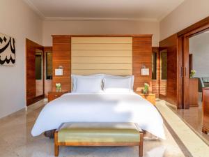 索瓦马死海瑞享Spa度假酒店的一间大卧室,配有一张白色的大床和长凳