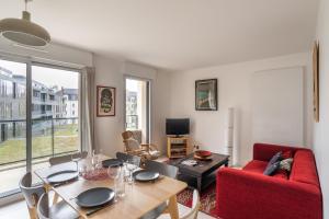 南特Le Bienveillant - T3 proche Jardin des Plantes的客厅配有桌子和红色沙发