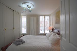 邓斯特布尔Harper Luxe Serviced Apartments Dunstable的一间卧室配有一张带白色床单和窗户的床。