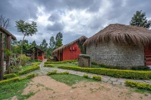 KanthalloorDeshadan Eco Valley Resort - An Eco friendly Mud House的一座带草屋顶的建筑和一座带小路的建筑