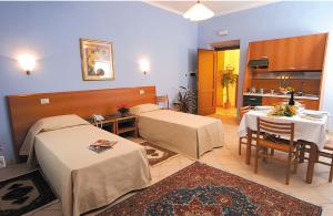 托雷佩利切普罗旺斯公寓式酒店的带两张床和一张桌子的房间以及一间厨房