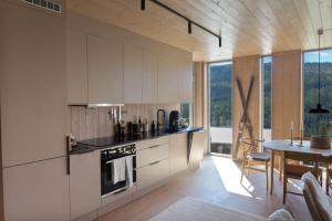 FavangNy leilighet på Kvitfjell Vest. Ski inn/ut的厨房配有白色橱柜、桌子和用餐室。