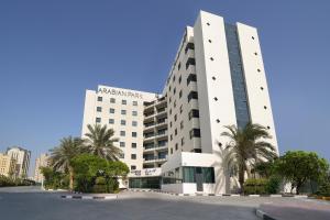 迪拜Arabian Park Dubai, an Edge by Rotana Hotel的一座白色的大建筑,前面有棕榈树