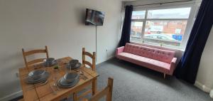 EtruriaStoke City House的一间带粉色沙发和桌子的用餐室