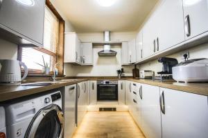 乔利Contractors accommodation in Chorley by Lancashire Holiday Lets的厨房配有白色橱柜、洗衣机和烘干机