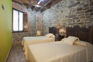 波拉·德莱纳Apartamentos El Aramo Asturias的一间卧室设有两张床和石墙