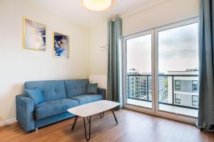 华沙Wola Lush Apartment的客厅设有蓝色的沙发和大窗户
