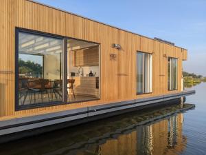 加赫Surla houseboat "Aqua Zen" Kagerplassen with tender的水边的房子,设有大窗户