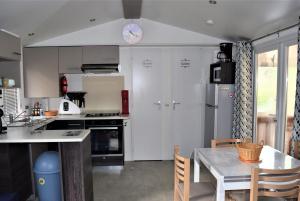 加斯泰Spacieux Mobil-home N°502 - 2 chambres - dans Camping 4 *的厨房配有白色橱柜、桌子和时钟