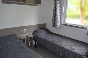 加斯泰Spacieux Mobil-home N°502 - 2 chambres - dans Camping 4 *的客房设有两张床、一张桌子和一扇窗户。
