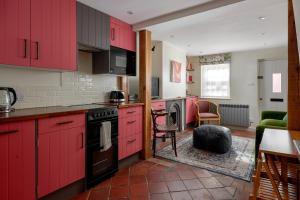 法纳姆Pearls Cottage的一间带红色橱柜的厨房和一间客厅