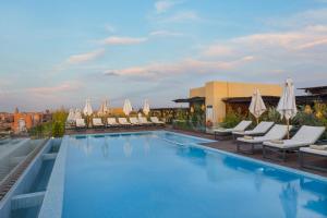 马拉喀什Longue vie Hotels的酒店游泳池设有椅子和遮阳伞