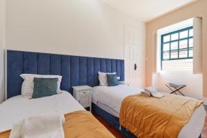 波尔图A Portuguesa Guest House的一间卧室设有两张床和蓝色床头板