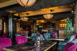 班多伦Holyrood Hotel - Leisure Centre & The Spa at Orchids的一间设有紫色椅子和桌子的餐厅和一间酒吧