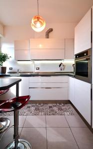 米兰San Siro Design Apartment的厨房配有白色橱柜和红色凳子
