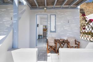 阿纳菲TA PLAGIA accommodation的一间配备有白色椅子和桌子的用餐室
