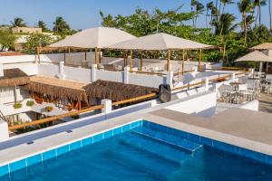 杰里科科拉Pousada Chez Toi的度假村的游泳池配有遮阳伞和桌子