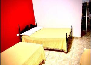 圣地亚哥-德尔埃斯特罗El Carmelo的一间卧室设有两张床和红色的墙壁