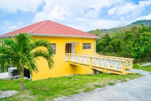 LaborieGlasgow Villa at La Mar的带阳台的黄色房屋和棕榈树