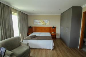 里约热内卢Barra da Tijuca - Flat Premium com cozinha, completinho, moderno e muito confortável的配有一张床和一把椅子的酒店客房