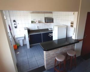 瓜拉派瑞Apartamento super arejado na Praia do Morro的一间带冰箱和两个凳子的小厨房
