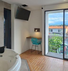 库库塔Hotel Macaw Cúcuta的带浴缸、窗户和椅子的浴室