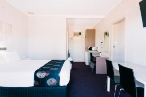 奥古斯塔港一品红汽车旅馆的酒店客房带一张床、一张桌子和椅子