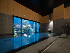 佐久市Hotel Route-Inn Saku Minami Inter的一座带大窗户的建筑中的游泳池